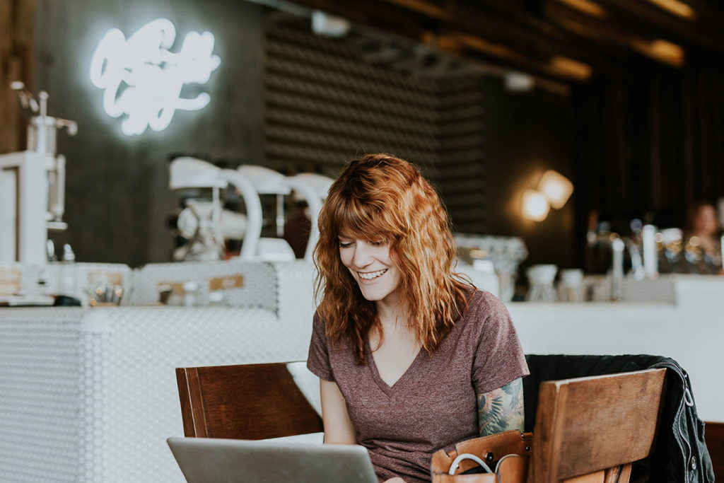 Picture of woman smiling using her laptop at a cafe