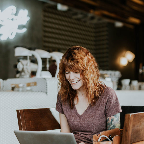 Picture of woman smiling using her laptop at a cafe